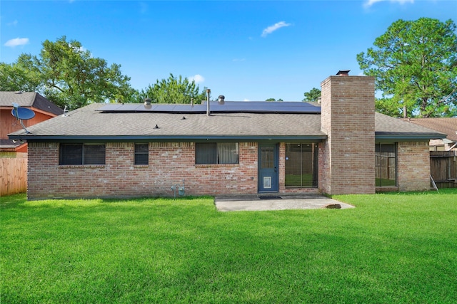 back of house with a patio, a lawn, and solar panels