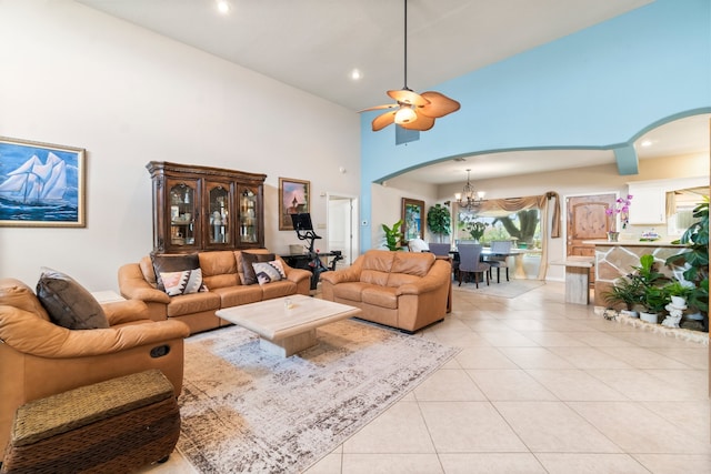 tiled living room featuring a towering ceiling and ceiling fan with notable chandelier