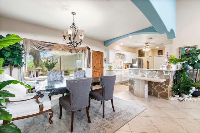 dining area with sink, light tile patterned floors, and ceiling fan with notable chandelier