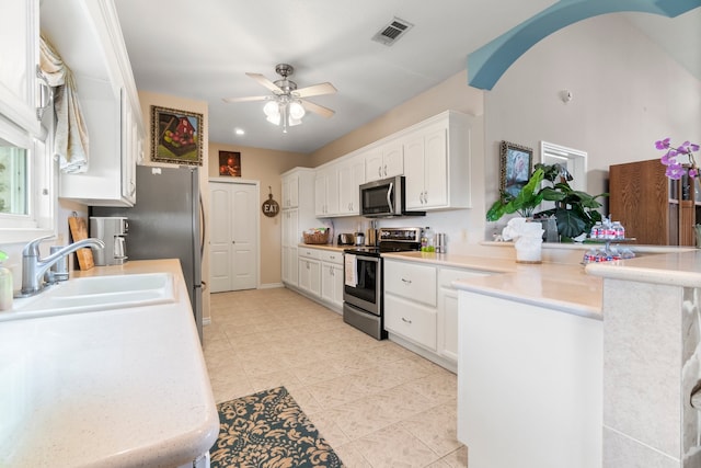 kitchen with kitchen peninsula, white cabinets, ceiling fan, appliances with stainless steel finishes, and sink