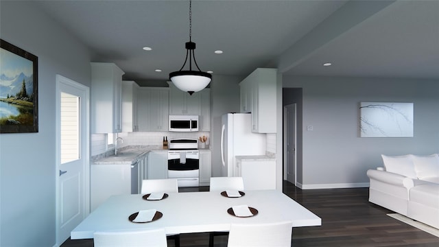 kitchen featuring dark wood-type flooring, hanging light fixtures, sink, backsplash, and white appliances