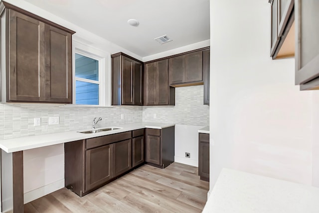 kitchen featuring decorative backsplash, sink, dark brown cabinets, and light hardwood / wood-style flooring