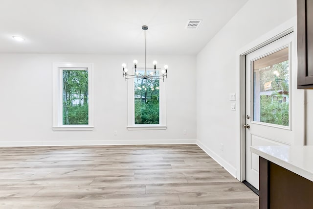 unfurnished dining area featuring a chandelier and light hardwood / wood-style flooring