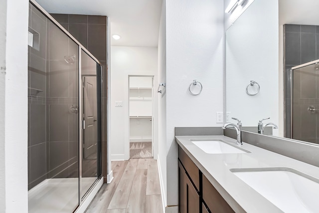 bathroom with hardwood / wood-style flooring, a shower with shower door, and vanity