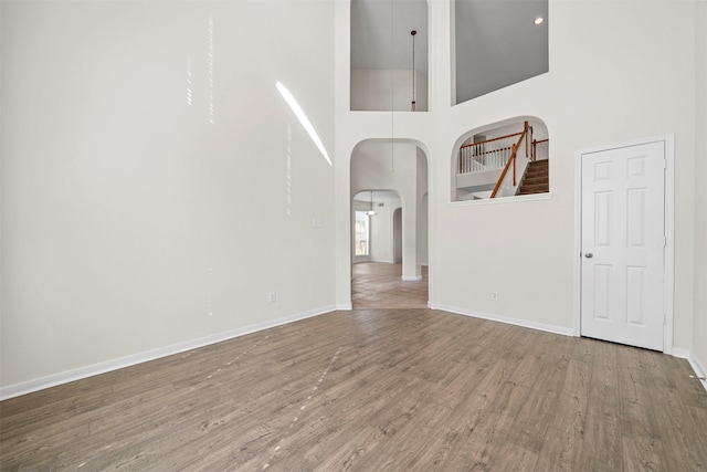 unfurnished room featuring a towering ceiling and wood-type flooring