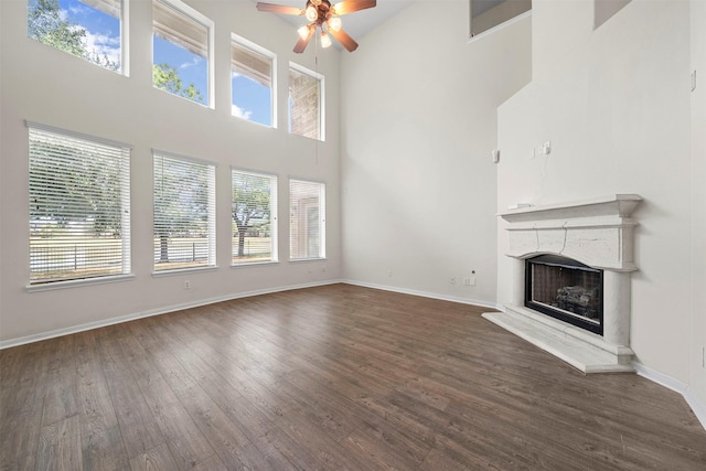 unfurnished living room featuring ceiling fan, a towering ceiling, and dark hardwood / wood-style flooring