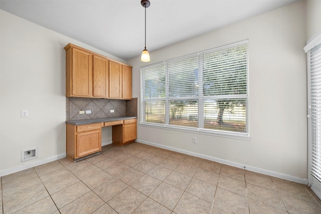 kitchen featuring built in desk, backsplash, light tile patterned floors, and decorative light fixtures