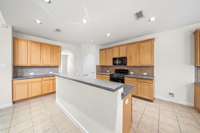 kitchen with light tile patterned floors, backsplash, black appliances, and a center island