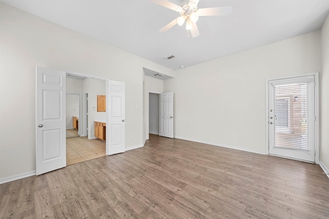 unfurnished bedroom featuring ensuite bath and light hardwood / wood-style floors