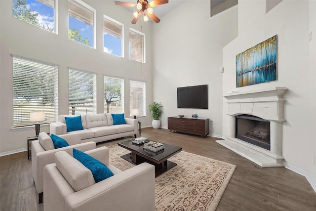 living room with a high ceiling, hardwood / wood-style floors, and ceiling fan