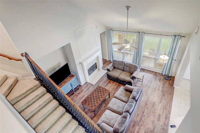 living room with ceiling fan, lofted ceiling, wood-type flooring, and a tiled fireplace