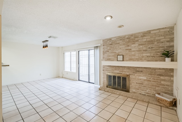 unfurnished living room with brick wall, a textured ceiling, light tile patterned floors, and a brick fireplace