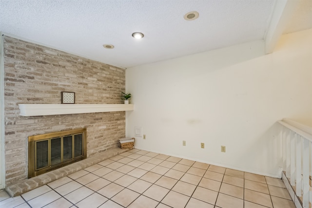 unfurnished living room with a textured ceiling, light tile patterned flooring, and a brick fireplace