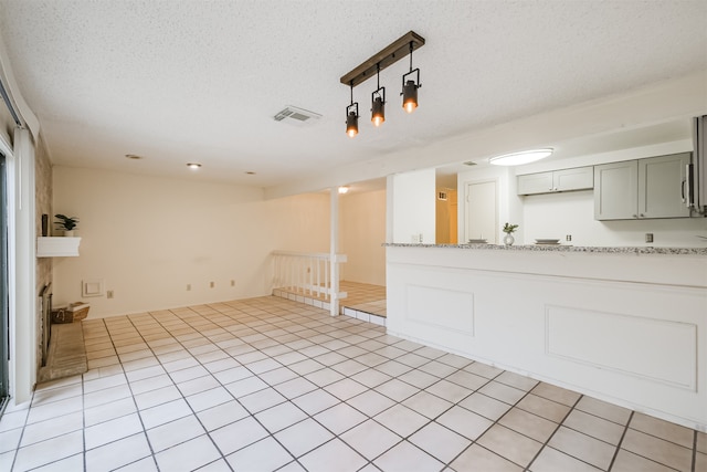 unfurnished living room featuring a textured ceiling and light tile patterned floors