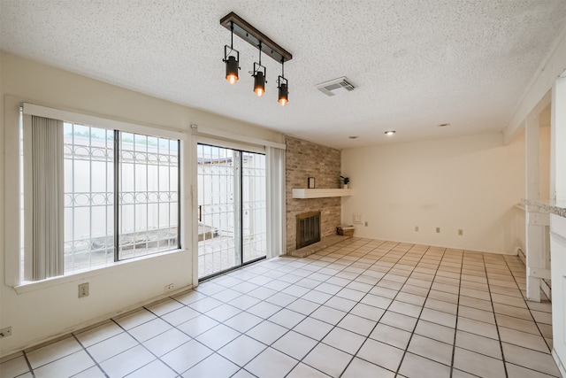 unfurnished living room featuring a brick fireplace, a textured ceiling, and light tile patterned floors