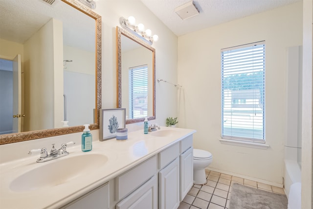 bathroom featuring toilet, a textured ceiling, vanity, and tile patterned floors