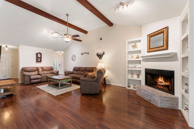 living room featuring vaulted ceiling with beams, dark hardwood / wood-style floors, a brick fireplace, built in features, and ceiling fan