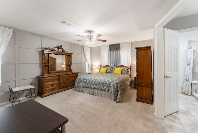 carpeted bedroom with ceiling fan and a textured ceiling