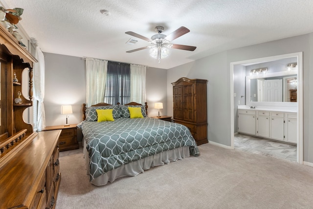 bedroom featuring sink, ensuite bath, a textured ceiling, light carpet, and ceiling fan