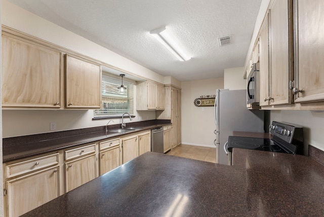 kitchen featuring sink, light brown cabinets, stainless steel appliances, and a textured ceiling