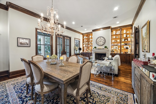 dining room with dark hardwood / wood-style floors, built in features, crown molding, and a notable chandelier