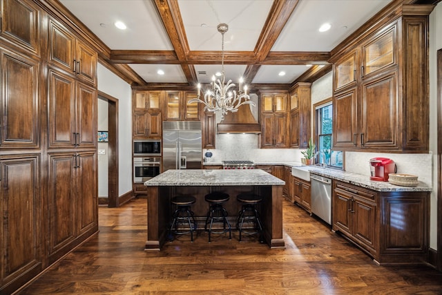 kitchen featuring built in appliances, custom exhaust hood, coffered ceiling, dark hardwood / wood-style floors, and a kitchen island