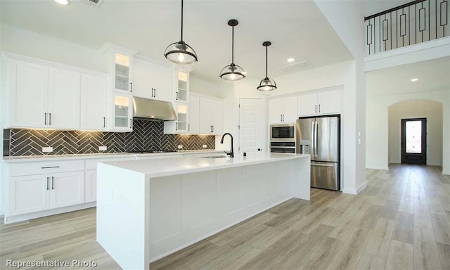 kitchen featuring sink, white cabinetry, appliances with stainless steel finishes, and a center island with sink