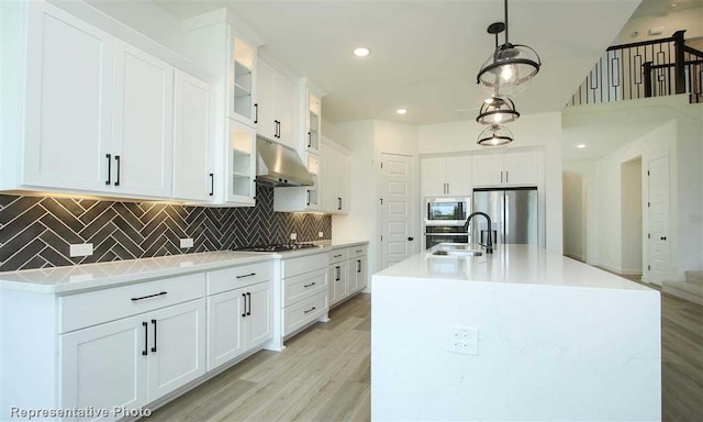 kitchen featuring stainless steel fridge with ice dispenser, white cabinetry, an island with sink, built in microwave, and sink