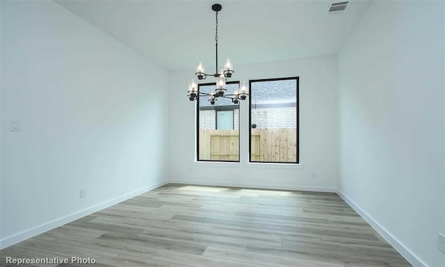 spare room with light hardwood / wood-style floors and a chandelier