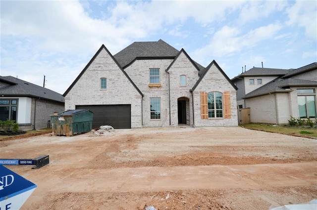 french provincial home featuring a garage and brick siding