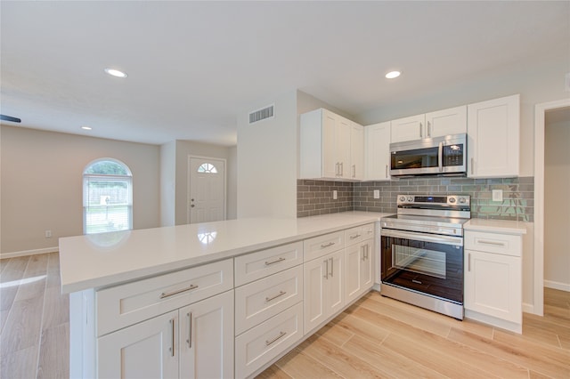 kitchen featuring white cabinetry, kitchen peninsula, light hardwood / wood-style floors, and stainless steel appliances