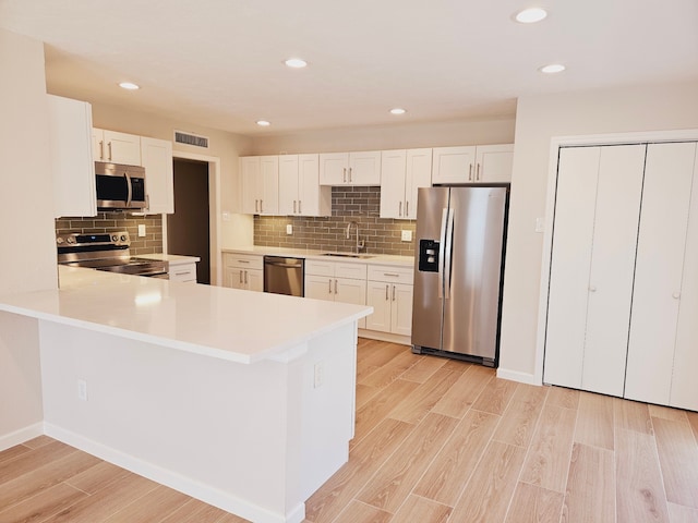 kitchen featuring white cabinetry, sink, light hardwood / wood-style floors, and stainless steel appliances