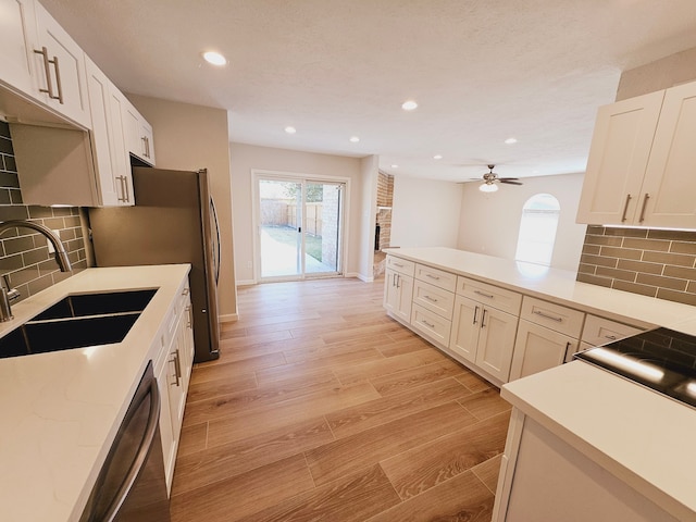 kitchen with tasteful backsplash, light wood-type flooring, sink, and white cabinets