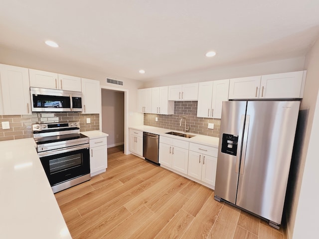 kitchen featuring light hardwood / wood-style flooring, appliances with stainless steel finishes, sink, and white cabinets