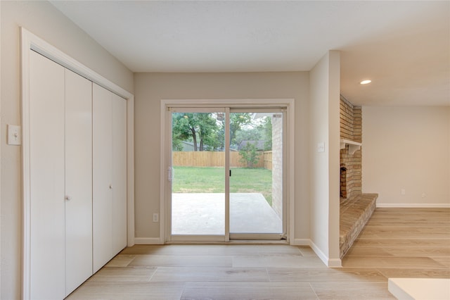 doorway featuring a fireplace and light hardwood / wood-style flooring