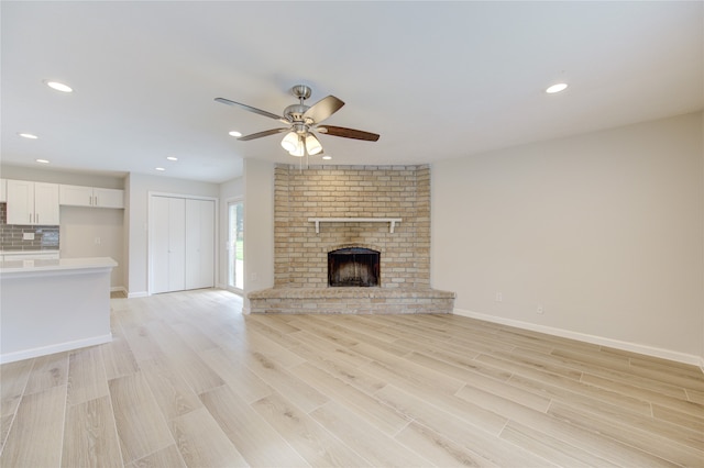 unfurnished living room featuring ceiling fan, light hardwood / wood-style floors, and a fireplace