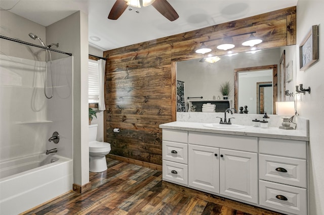 full bathroom with shower / bathing tub combination, hardwood / wood-style floors, wood walls, vanity, and ceiling fan