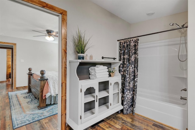 bathroom featuring wood-type flooring, shower / bathtub combination with curtain, and ceiling fan