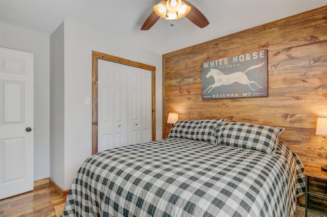 bedroom with a closet, wooden walls, and ceiling fan