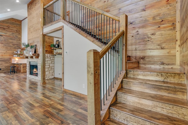 stairs with wood walls, a fireplace, hardwood / wood-style floors, and vaulted ceiling