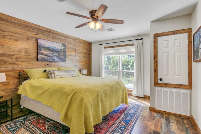 bedroom featuring wooden walls, ceiling fan, and dark hardwood / wood-style floors