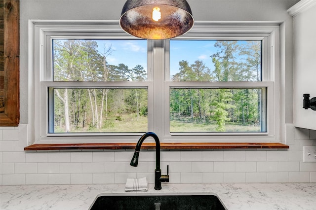 details featuring decorative backsplash, light stone countertops, and sink