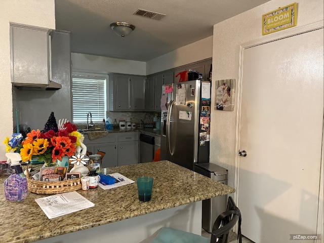 kitchen with kitchen peninsula, decorative backsplash, stainless steel fridge with ice dispenser, gray cabinetry, and sink