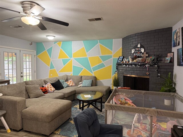 living room featuring french doors, a brick fireplace, a textured ceiling, and ceiling fan