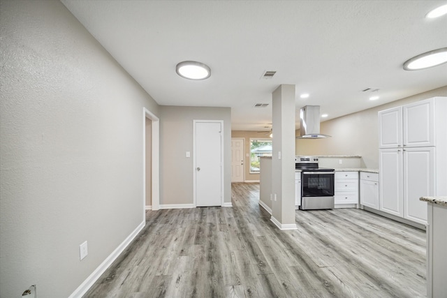 kitchen featuring light hardwood / wood-style floors, stainless steel range with electric stovetop, wall chimney exhaust hood, and white cabinets