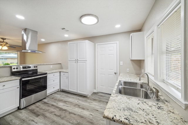 kitchen featuring island exhaust hood, stainless steel range with electric stovetop, sink, light wood-type flooring, and white cabinetry