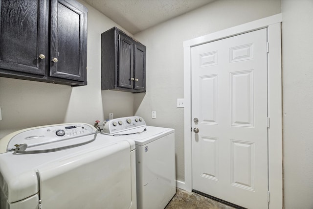 clothes washing area featuring a textured ceiling, washing machine and dryer, and cabinets