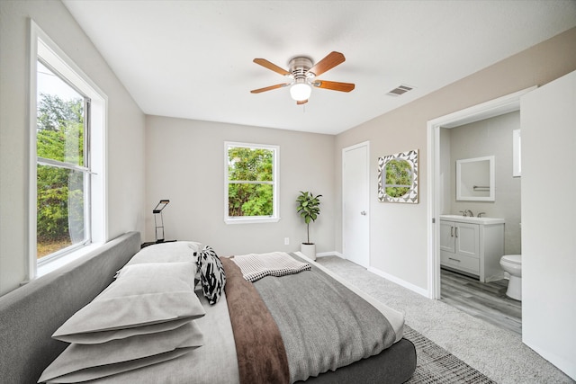 bedroom with connected bathroom, ceiling fan, and light hardwood / wood-style floors