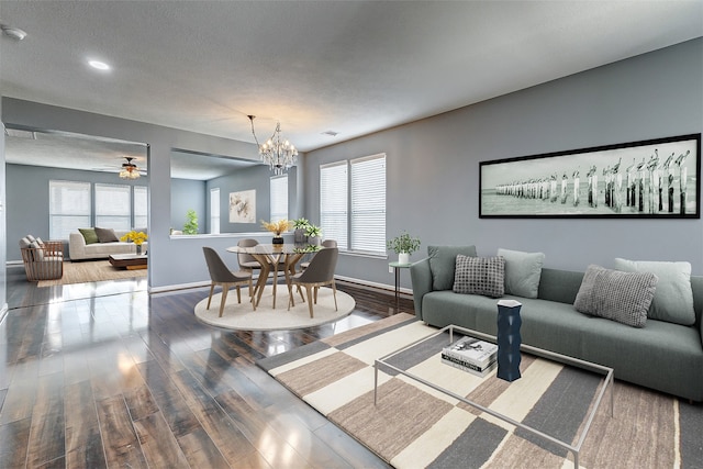 living room with hardwood / wood-style floors, ceiling fan with notable chandelier, and a textured ceiling