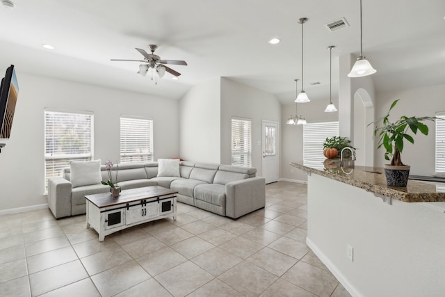 tiled living room featuring ceiling fan with notable chandelier and a wealth of natural light